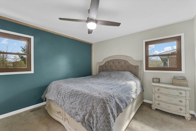 bedroom featuring light carpet, visible vents, baseboards, and ceiling fan