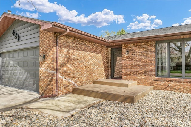 property entrance with brick siding, driveway, and a garage