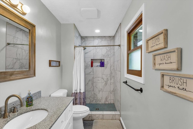 full bathroom featuring a tile shower, vanity, and toilet