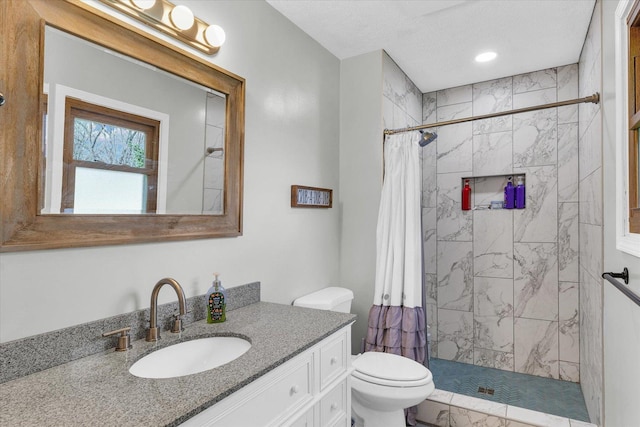 bathroom featuring toilet, tiled shower, and vanity