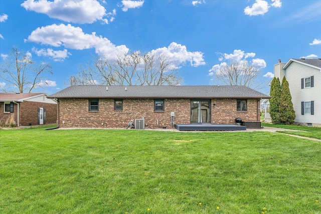 rear view of property with cooling unit, a lawn, a patio area, and brick siding