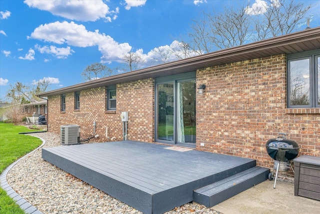 back of property featuring central air condition unit, a deck, and brick siding