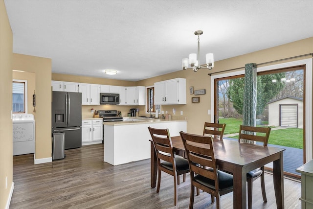 dining space featuring dark wood-type flooring, baseboards, washer / dryer, and a notable chandelier