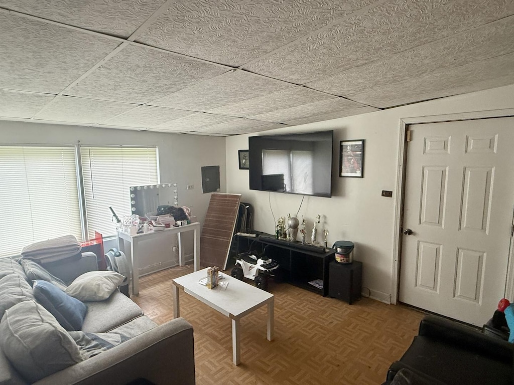 living area with electric panel and a paneled ceiling