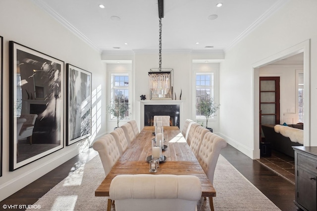 dining room featuring baseboards, ornamental molding, dark wood finished floors, recessed lighting, and a lit fireplace