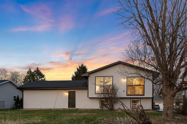 split level home with a shingled roof and a front yard