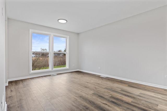 unfurnished room with visible vents, baseboards, and wood finished floors