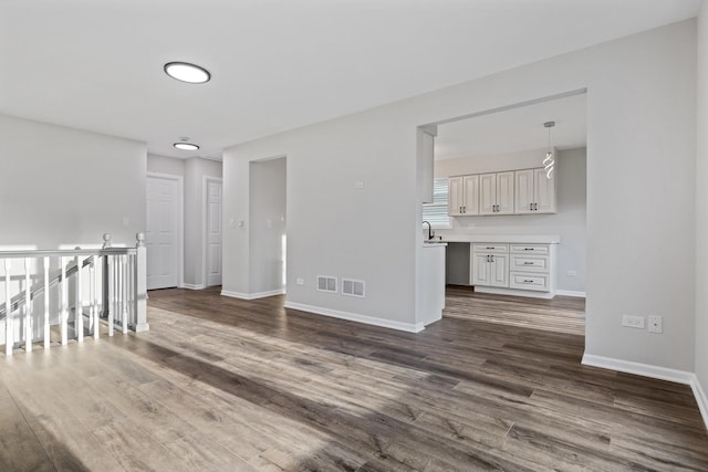 spare room with dark wood-style flooring, baseboards, a sink, and visible vents