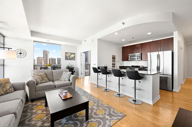 living area with a city view, light wood finished floors, baseboards, and recessed lighting