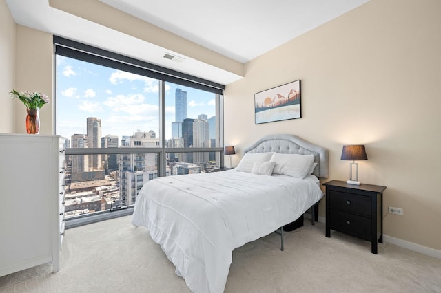 bedroom with visible vents, baseboards, a view of city, and light carpet