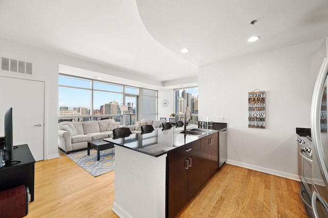 kitchen with a view of city, a peninsula, visible vents, light wood finished floors, and a sink
