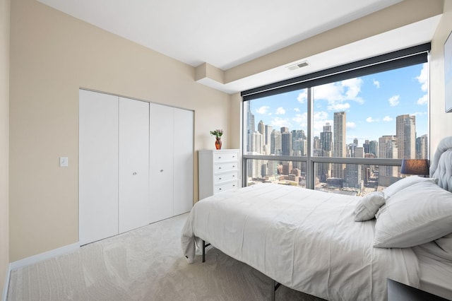 carpeted bedroom with visible vents, a closet, and a city view
