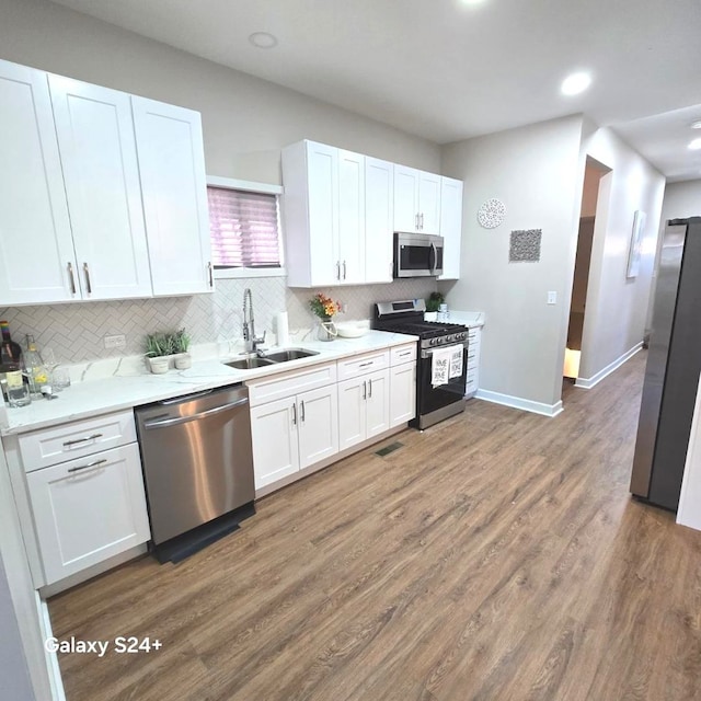 7825 S Saint Lawrence Ave, Chicago, IL 60619 - kitchen with white cabinets, stainless steel appliances, a sink, backsplash, and wood finished floors
