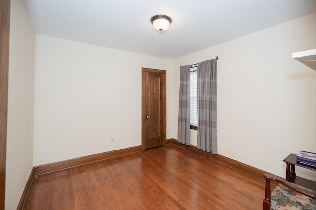 spare room featuring wood finished floors and baseboards