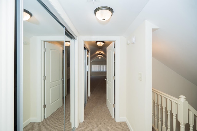 corridor with baseboards, an upstairs landing, and light carpet
