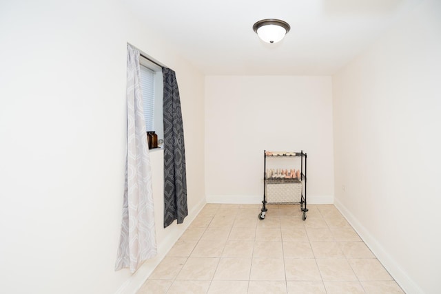 hall featuring baseboards and light tile patterned flooring