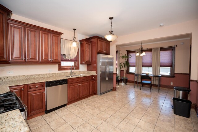 kitchen with light tile patterned floors, light stone countertops, a sink, hanging light fixtures, and stainless steel appliances