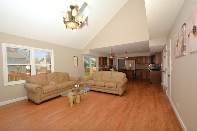 241 Butte View Dr N, Bolingbrook, IL 60490 - living room featuring a chandelier, high vaulted ceiling, baseboards, and light wood-style flooring