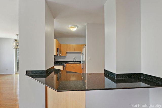 21 W Chestnut St Unit 1509, Chicago, IL 60610 - kitchen featuring appliances with stainless steel finishes, dark stone countertops, light wood-style flooring, and a peninsula
