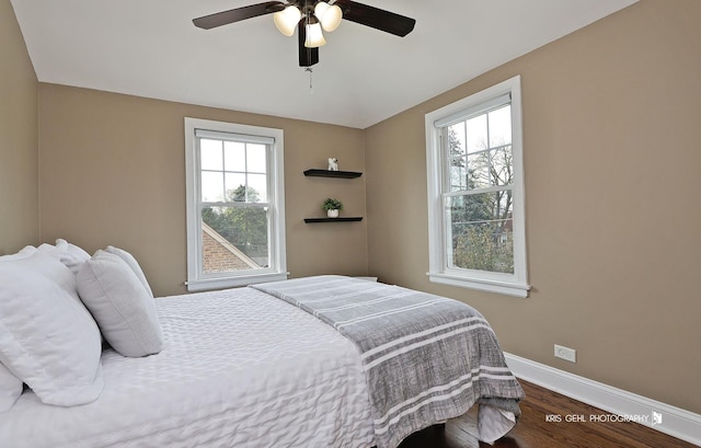 bedroom featuring baseboards, ceiling fan, wood finished floors, and multiple windows
