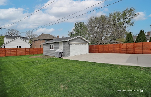 exterior space featuring a fenced backyard, a patio area, a yard, and a detached garage