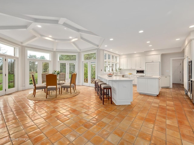 8 Longwood Dr, Burr Ridge, IL 60527 - kitchen featuring light tile patterned floors, light countertops, stainless steel microwave, white cabinetry, and a kitchen island
