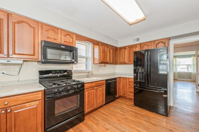 1919 Sunnyside Ave, Westchester, IL 60154 - kitchen featuring black appliances, light wood-style floors, backsplash, brown cabinets, and light countertops