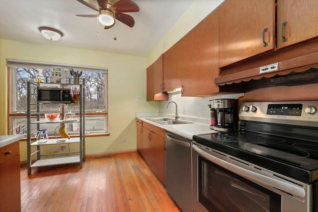 5770 N Forest Glen Ave, Chicago, IL 60646 - kitchen with a sink, light countertops, under cabinet range hood, light wood finished floors, and stainless steel appliances