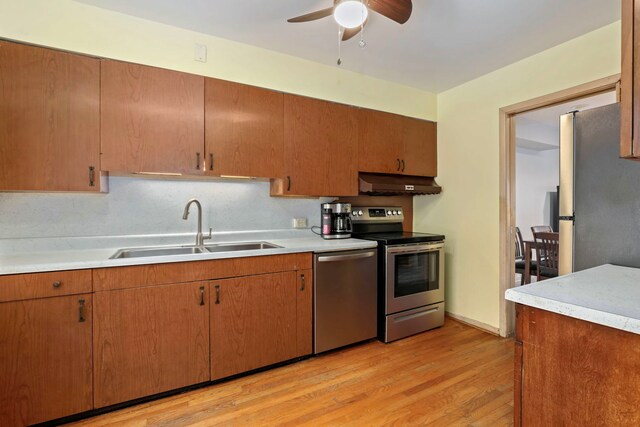 5770 N Forest Glen Ave, Chicago, IL 60646 - kitchen with light wood-type flooring, under cabinet range hood, light countertops, a sink, and stainless steel appliances