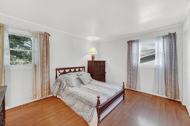 bedroom with wood finished floors and crown molding