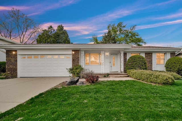 single story home with brick siding, an attached garage, driveway, and a lawn
