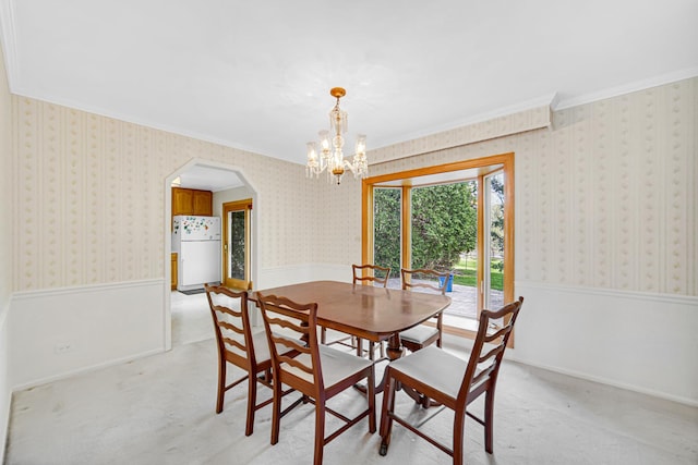 dining space with crown molding, arched walkways, wallpapered walls, a chandelier, and a wainscoted wall