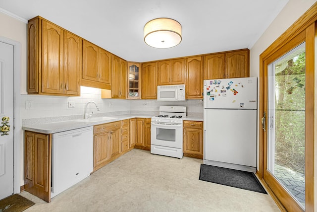 kitchen featuring white appliances, a sink, light countertops, backsplash, and crown molding