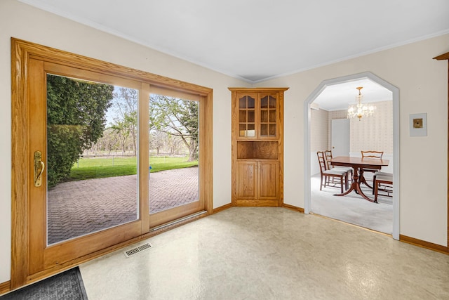 entryway with a chandelier, baseboards, arched walkways, and ornamental molding