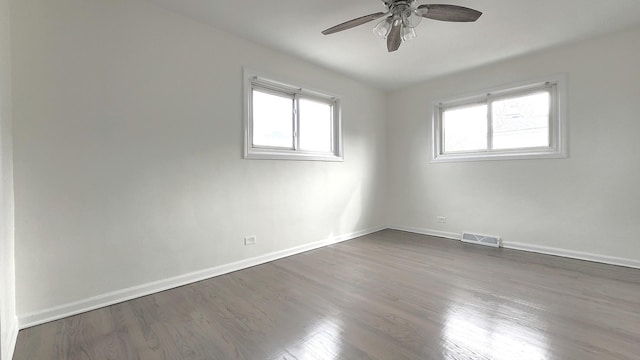 spare room with wood finished floors, baseboards, a ceiling fan, and visible vents