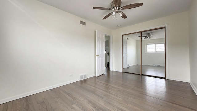 unfurnished bedroom featuring visible vents, baseboards, a closet, and wood finished floors
