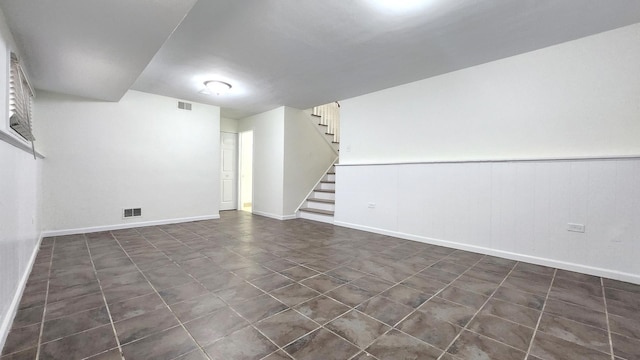 finished below grade area featuring visible vents, baseboards, and stairs
