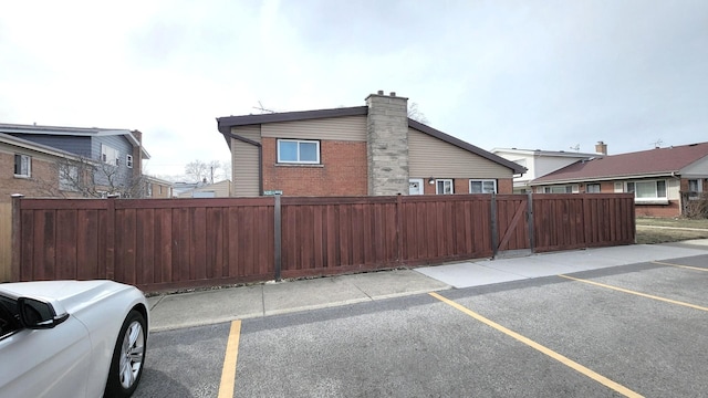 view of home's exterior featuring brick siding, uncovered parking, and fence