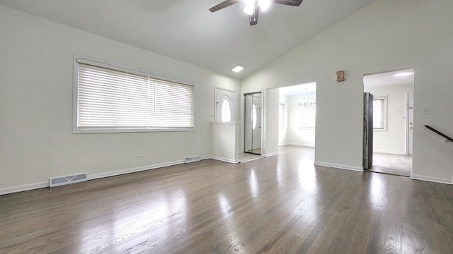 interior space featuring dark wood-type flooring, ceiling fan with notable chandelier, high vaulted ceiling, and visible vents