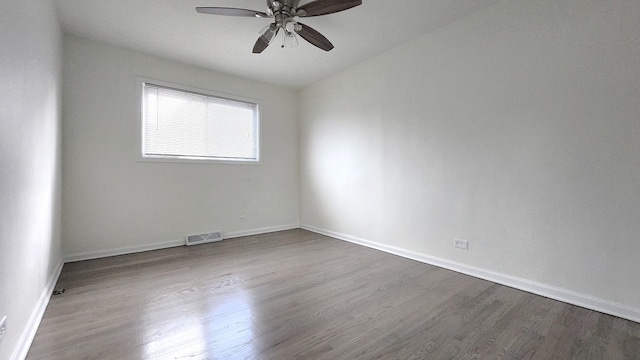 unfurnished room featuring dark wood-style floors, baseboards, visible vents, and ceiling fan