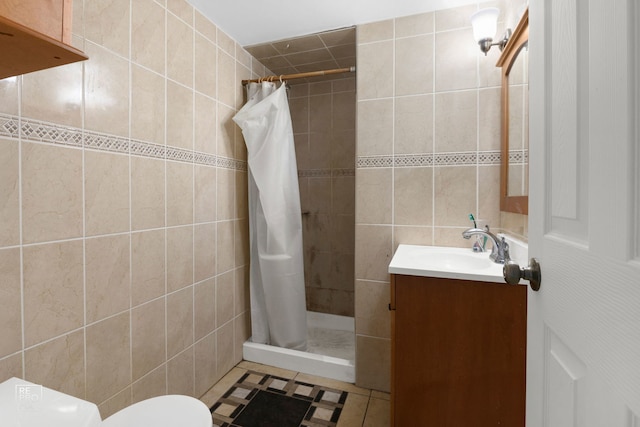 bathroom with toilet, vanity, a shower stall, and tile walls