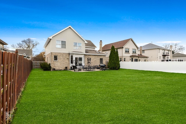 rear view of property featuring a patio, a yard, a fenced backyard, and brick siding