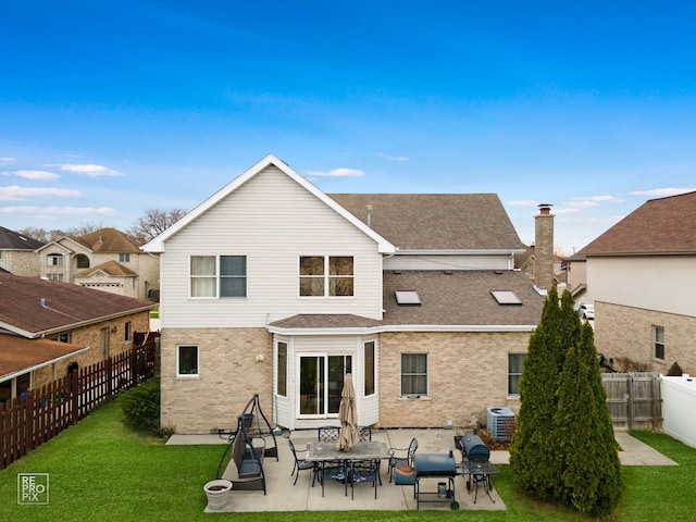 back of property featuring a patio, roof with shingles, central air condition unit, brick siding, and a yard