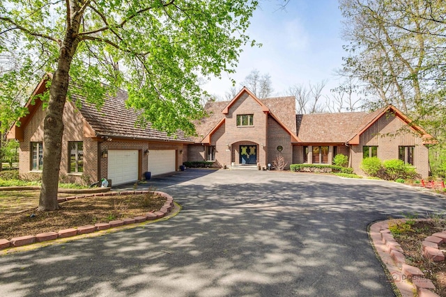 view of front facade with asphalt driveway, brick siding, and an attached garage
