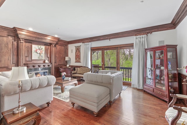 living area featuring ornamental molding, light wood finished floors, a high end fireplace, and recessed lighting