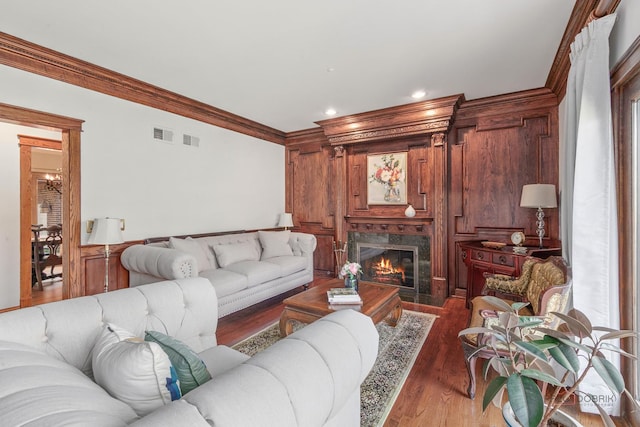 living area featuring crown molding, wood finished floors, a premium fireplace, recessed lighting, and wood walls