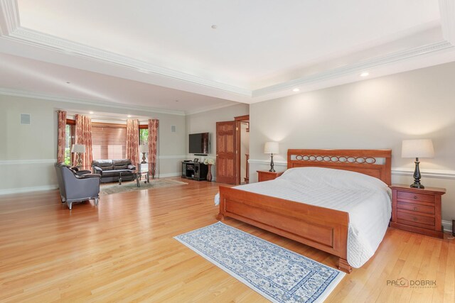 bedroom featuring light wood finished floors, a tray ceiling, crown molding, recessed lighting, and baseboards