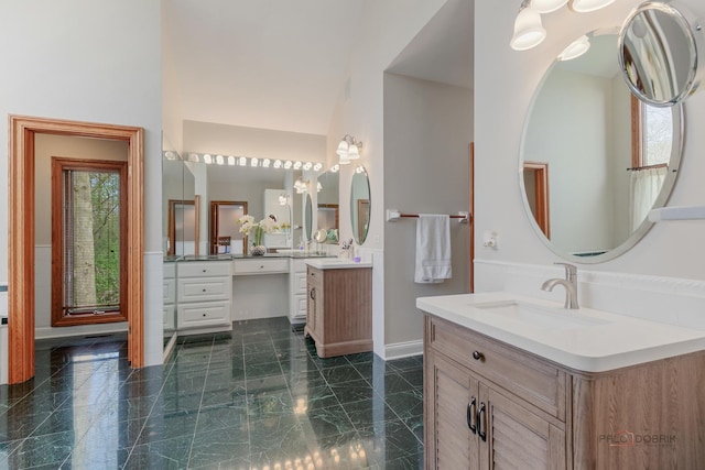full bathroom featuring two vanities and baseboards
