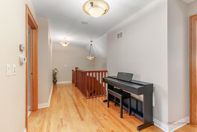 corridor with an upstairs landing, wood finished floors, and baseboards