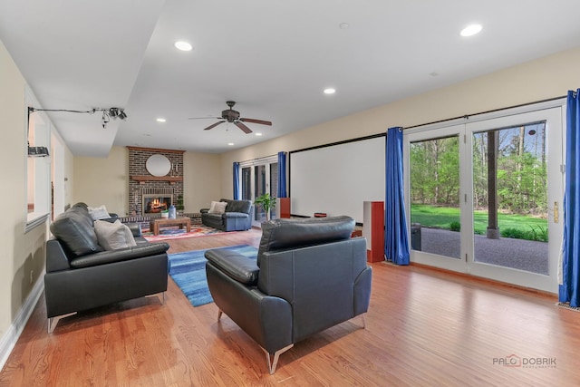 living room featuring light wood finished floors, recessed lighting, ceiling fan, baseboards, and a fireplace